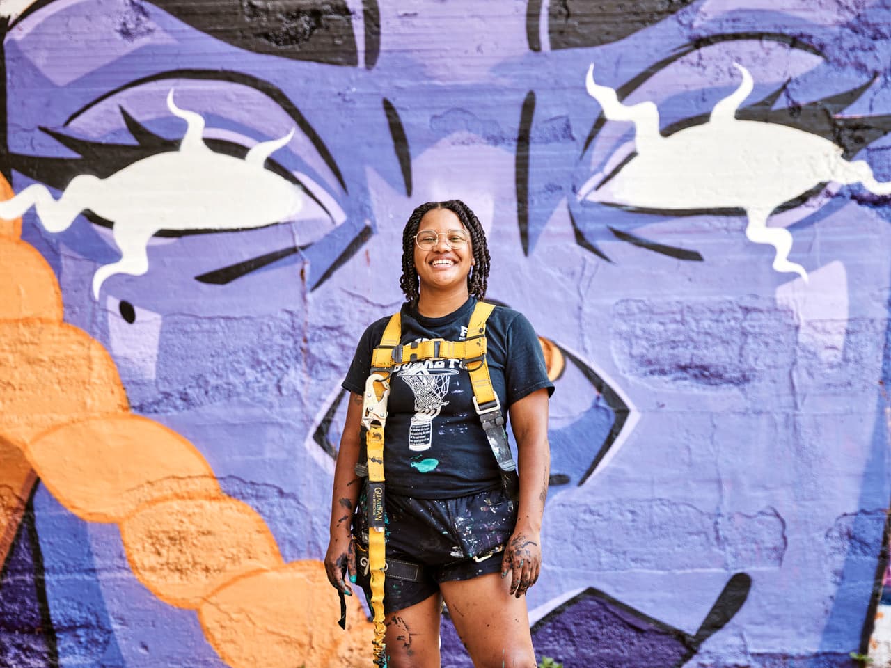 A person stands in front of a colorful mural.