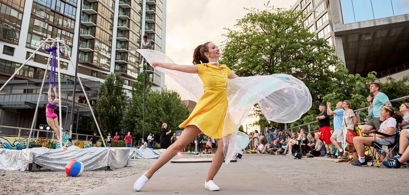 A woman dances in front of a crowd in a bright yellow dress.